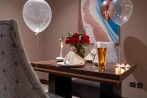 a table with two balloons and a glass of beer at Lilac Park Hotel in Tabuk