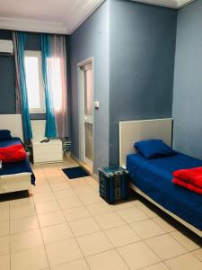 1 dormitorio con 2 camas y pared azul en Hotel Marhaba - Beb Bhar Tunis en Túnez