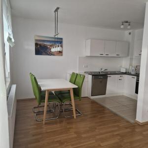 a small kitchen with a table and green chairs at Ferienwohnung Rügen Breege in Breege