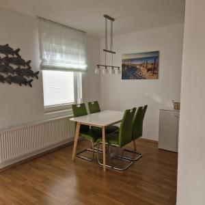 a dining room with a table and green chairs at Ferienwohnung Rügen Breege in Breege