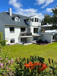 a white house with a yard with flowers at COZY APPARTMENT Free parking in Reykjavík