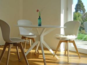 a table with white chairs and a vase with a flower on it at Ferienwohnung Peterberg in Kirchzarten