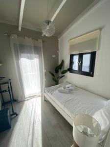 a white bedroom with a bed and a window at Ivory Style Maisonette near Downtown in Heraklio