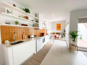 a kitchen with white cabinets and a brick wall at Casa Longa Faro Entire House - Plunge Pool and Terrace in Faro