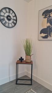 una mesa con una planta al lado de un reloj en Premium CITY APARTMENT near Harry Potter Studio and Luton Airport en Hemel Hempstead