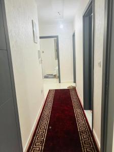 - un couloir avec un tapis rouge au sol dans l'établissement شقق إقامة الامل, à Oulad Hamdane