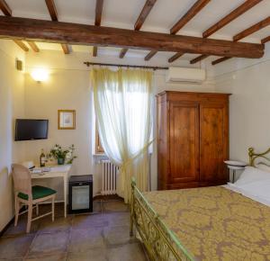 sypialnia z łóżkiem, biurkiem i telewizorem w obiekcie Donna Nobile w mieście San Gimignano