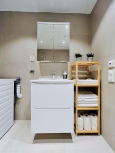 een badkamer met een wastafel en een plank met handdoeken bij Sleek 1BD Apt with Sea View in Tromsø