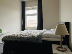 una camera da letto con un letto con una lampada e una finestra di Ferienwohnung PIER 4 in Cuxhaven a Cuxhaven