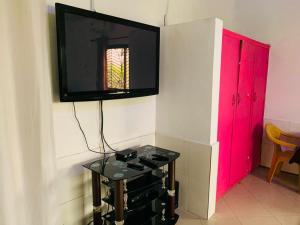 un televisor en una pared con una mesa con un televisor en ella en HOMELY GUEST HOUSE, en Agona