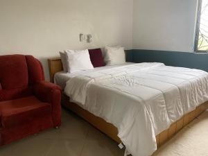 ein Schlafzimmer mit einem Bett und einem roten Stuhl in der Unterkunft HOMELY GUEST HOUSE in Agona