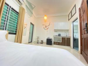 a bedroom with a large white bed and a kitchen at Easystay Apartment - 154 Đinh Thôn, Mỹ Đình, Hà Nội in Hanoi