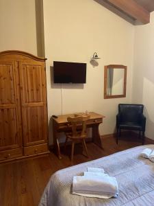 - une chambre avec un lit, un bureau et une télévision dans l'établissement La corte dell'ulivo, à Polazzo