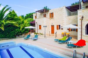a pool with chairs and umbrellas next to a house at Villa Marcos Chara in Astérion