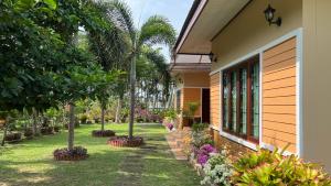 a garden next to a house with trees and flowers at Malinee Villa Phuket in Bang Tao Beach