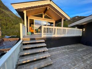 une maison avec une terrasse couverte en bois accessible par des escaliers. dans l'établissement Flott hytte i Morfjorden, Laupstad, à Laupstad