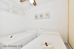two beds in a room with white walls at Las Damas 3B Beach Front - Pool & Parking in Benidorm +25 photos