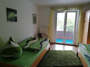 a bedroom with a green bed and a window at Ferienwohnung Renner ca 100 qm in Mühlingen