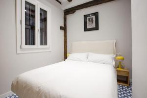 a white bedroom with a white bed and a window at Etxeburu (Apto Casco Viejo) in Bilbao