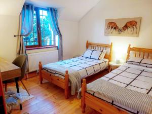 1 dormitorio con 2 camas, escritorio y ventana en Knockmanagh Holiday Home, en Kilcummin