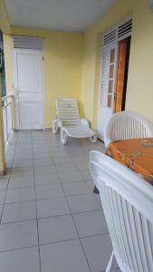 a room with two white chairs and a porch at La villa du manguier in Le Vauclin