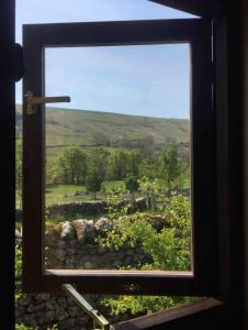 een raam met uitzicht op een veld buiten bij Wharfe Pod in Kettlewell