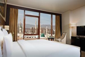 una camera da letto con un grande letto bianco e una grande finestra di Pullman Zamzam Madina a Medina