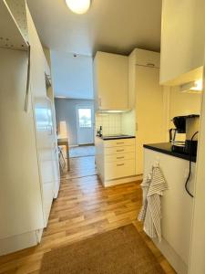 eine Küche mit weißen Schränken und Holzböden in der Unterkunft Lägenhet i centrala Lidköping - MyHostel in Lidköping