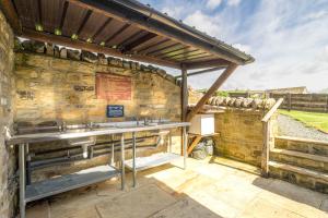 een stenen gebouw met een stenen muur en een wastafel bij Wharfe Pod in Kettlewell