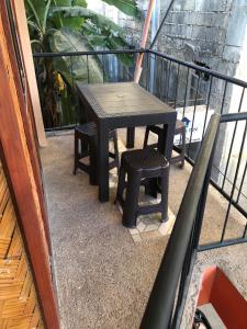 a table and a stool sitting on a balcony at Wakim’s INN in Coron