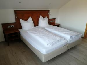 a bed with white sheets and pillows in a room at Hotel Landgut Jungfleisch in Gries