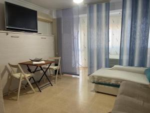 1 dormitorio con cama, mesa y TV en Apartamentos Terrasol Plazamar, en Torre del Mar