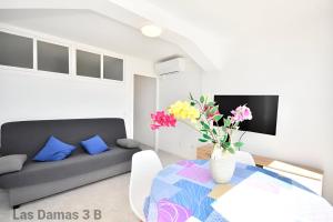 a living room with a couch and a table with flowers at Las Damas 3B Beach Front - Pool & Parking in Benidorm