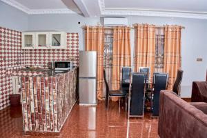 a dining room with a table and chairs and curtains at Becky Best Apartments in Limbe