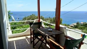 einen Tisch und Stühle auf einem Balkon mit Meerblick in der Unterkunft zacharoularooms3 in Manganítis