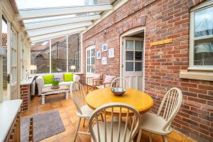 a patio with a table and chairs and a brick wall at Mahonia Cottage in Burnham Market