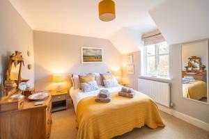 a bedroom with a bed and a desk and a mirror at Mahonia Cottage in Burnham Market