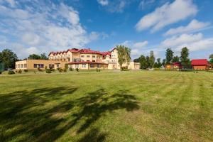 ein großes Grasfeld mit einem großen Gebäude im Hintergrund in der Unterkunft BURSZTYN - BERNSTEIN SPA & Wellness in Dąbki