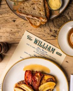 um prato de comida numa mesa com um livro e pão em The William em Londres