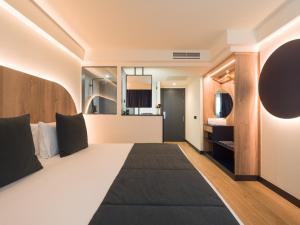 Habitación de hotel con cama grande y espejo en Sercotel Playa Canteras en Las Palmas de Gran Canaria