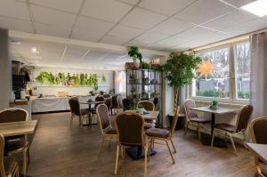 a dining room with tables and chairs and plants at Jantar Resort in Szczecin