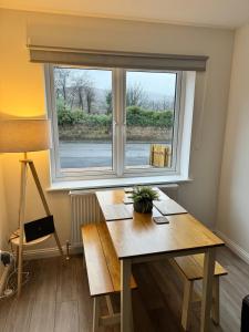 ein Esszimmer mit einem Tisch und einem Fenster in der Unterkunft Inchmurrin Townhouse, Loch Lomond in Bonhill