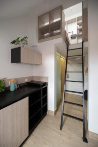 a kitchen with black cabinets and a ladder in a room at Studio Kampus Garnizon in Gdańsk