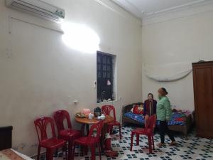 two people standing in a room with a table and chairs at Mr. Hợp in Kim Côn
