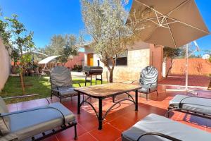 a patio with a table and chairs and an umbrella at Villa Alambra Marrakech sur Atlas, Piscine privée in Marrakesh