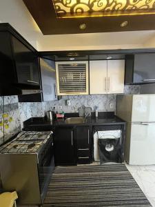 a kitchen with black cabinets and a sink and a stove at Porto said بورتوسعيد شاليه غرفه وصاله in Port Said