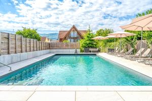 a swimming pool with chairs and umbrellas at Adler Landhotel in Buergstadt