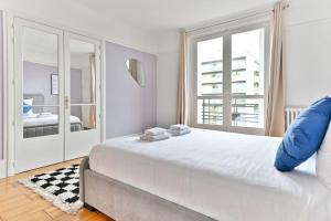ein weißes Schlafzimmer mit einem großen Bett und einem Fenster in der Unterkunft Appartement Luxueux Porte Maillot - Neuilly - III in Neuilly-sur-Seine
