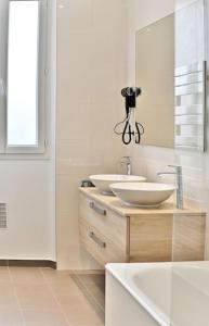 a white bathroom with two sinks and a mirror at Appartement Luxueux Porte Maillot - Neuilly - III in Neuilly-sur-Seine