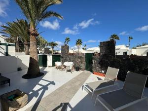 een patio met 2 stoelen en een palmboom bij Luxury Bungalow Playa Roca in Costa Teguise